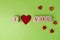 Valentine hearts and rustic alphabet blocks that spell out I Love You on greenery background. Top view. Copy space for