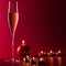 Valentine mood with a glass of champage and candles with fire and flame on a red textured background.