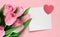 Valentine Mother`s day greeting card with pink tulips and blank paper note with heart on pink background.