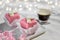 Valentine petit fours with marzipan icing and cream flowers. Espresso coffee in glass cup. Garland of lights on white