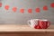 Valentine`s day background with coffee cups, heart shape chocolate and garland