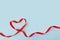 Valentine\'s Day background February 14th. Heart made of red  satin ribbon on blue background.