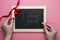 Valentine`s day background. Female hands writting I love you message on chalkboard frame, hearts and red ribbon, flat