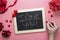 Valentine`s day background. Female hands writting I lvoe you message on chalkboard frame, hearts and red ribbon, flat