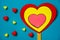 VALENTINE`S DAY background. A large multi-colored heart on a stick, red and yellow silicone hearts a blue background