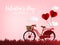 Valentine`s Day background with red bicycle with red heart shape balloon on grass and red sky with cloud background.