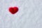 Valentine`s day background with a red wool felted heart lying on the white snow