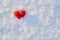 Valentine`s day background with a red wool felted heart lying on the white snow