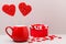 Valentine`s day background. Two candy hearts in a red Cup and a scattering of small hearts on a light gray background