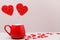 Valentine`s day background. Two candy hearts in a red Cup and a scattering of small hearts on a light gray background