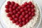 Valentine`s Day Cake, Wedding Cake. Beautiful cake with natural berries, laid out in the shape of a heart, on a coconut background