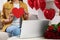 Valentine\'s day celebration in long distance relationship. Woman holding red paper heart while having video chat with her