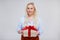 Valentine`s day or christmas concept - beautiful plus size blonde woman holding gift box over gray