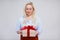 Valentine`s day or christmas concept - portrait of beautiful and elegant plus size blonde woman opening gift box over gray