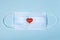 Valentine`s day composition. Medical face protective mask and red and white hearts on blue background. New normal and coronavirus