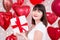 Valentine`s day concept - happy dreaming woman with gift box over red balloons background