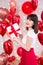 Valentine`s day concept - happy dreaming woman holding gift box over red balloons background