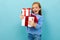 Valentine`s day concept. little girl barely holds two gifts on a light blue background