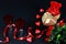 Valentine`s day concept. Teddy bear in heart shaped gift box with candle and red wineglass on black background.