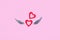 Valentine`s day concept. Two red hearts with silver wings on a pink background