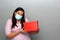Valentine`s day in contingency covid-19. latin woman with protection mask clinical use and red box of ragalo
