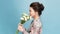 Valentine`s Day - Dreaming Voluptuous Young Woman with Bouquet of Flowers while standing against blue background