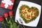 Valentine`s day food. Heart shaped pizza next to a gift and red roses, on a dark wooden background. Valentine`s day concept Top