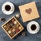 Valentine`s Day gift - candy box with chocolate sweets and two cups of coffee on dark background