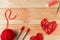 Valentine`s Day Handmade Red Thread Hearts and needlework supplies on wooden background.