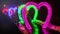 Valentine`s Day. Neon hearts. The tunnel of lovers. Timelapse people are photographed near colored garlands in the shape