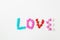Valentine`s day pattern background flat lay top view of bright candies in the shape of the word love scattered on a white