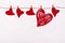 Valentine`s Day. Red hearts of felt of different sizes are hung on a rope on a white background. Concept of exclusion