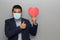 Valentine`s new normal. Formal Latin man with blue jacket, clinical use mask and red heart.