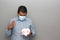 Valentine`s new normal. Latin man with blue shirt, clinical use protection mask and heart box of chocolates