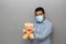 Valentine`s new normal. Latino man with blue shirt, clinical use protection mask and teddy bear