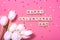 Valentine sign on wooden cubes and white tulip flower on pink background. Love and Valentine day concept.