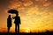 Valentine silhouette of Man and woman holding umbrella in evening sunset