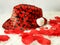 Valentines black hat with many red hearts, on white shag carpet, rose petals, small white pillow hat