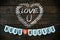 Valentines crafting. Chalk drawn Valentine\'s wreath, Love U lettering. Banner HUGS and KISSES, red paper heart on dark barn wood