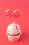 Valentines cupcake cream cheese frosting decorated with heart candy lollipops on the red background.