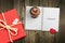 Valentines day card background with red present gift box on wooden table next to chocolate cupcake love heart shape cookie and