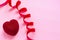 Valentines day concept. Red velvet heart shaped cake on pink surface with red velvet ribbon