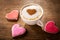 Valentines day.  Cup of cappuccino coffee with drawn heart and colorful heart shaped cookies, top view