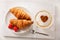 Valentines day.  Cup of cappuccino coffee with drawn heart and fresh croissants, top view