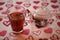 Valentines day drink photography of a glass teapot and cup filled with hot apple spice flavor tea on love heart cloth