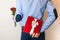 Valentines day gift surprise,man hiding gift and holding red rose bouquet