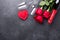 Valentines day greeting card. Red roses, champagne, glasses and textile hearts on stone background. Top view