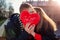 Valentines day kiss. Man and woman hiding behind heart shaped pillow with writing I love you outdoors