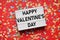 Valentines day lightbox sign on red paper background with confetti