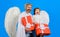 Valentines day. Little cupid boy and bearded man in angel wings with valentine gift. Father and son.